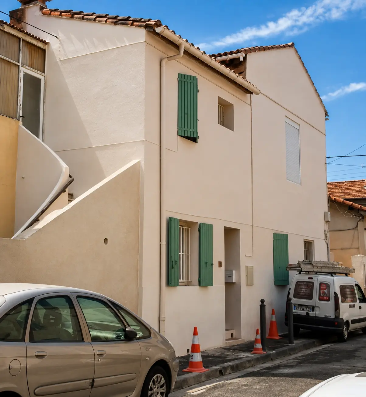Façade de maison de village rénovée et repeinte avec volets verts restaurés